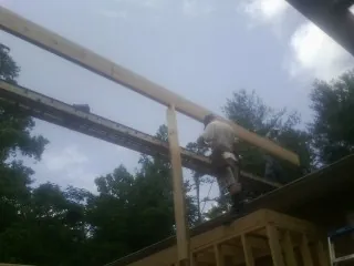 Carpenter setting a ridge beam over a new addition frame — Ice Dam Removal by Roofing Brothers in Ozawkie