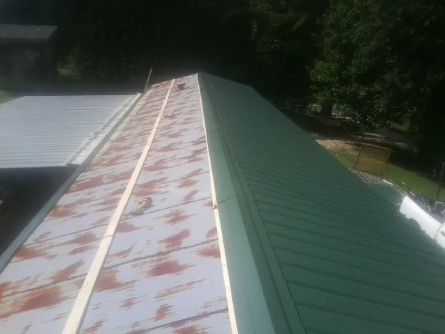 Old rusted panels beside newly installed green metal roofing — Wind Damage Roof Repair by Roofing Brothers in Ozawkie