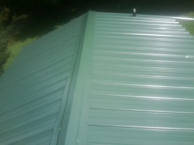 New green metal panels meeting at the ridge of a roof — Flat Roof Repair work by our crew in Ozawkie