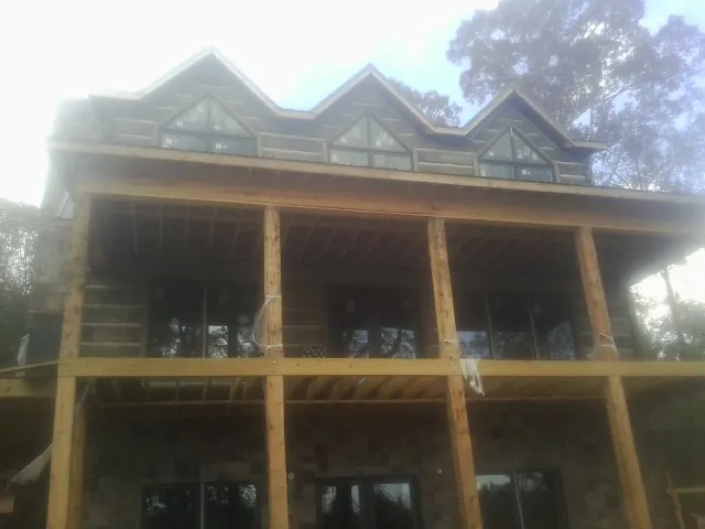 Dormers and porch framing on a large log home under construction — Roof Coating work by our crew in Ozawkie