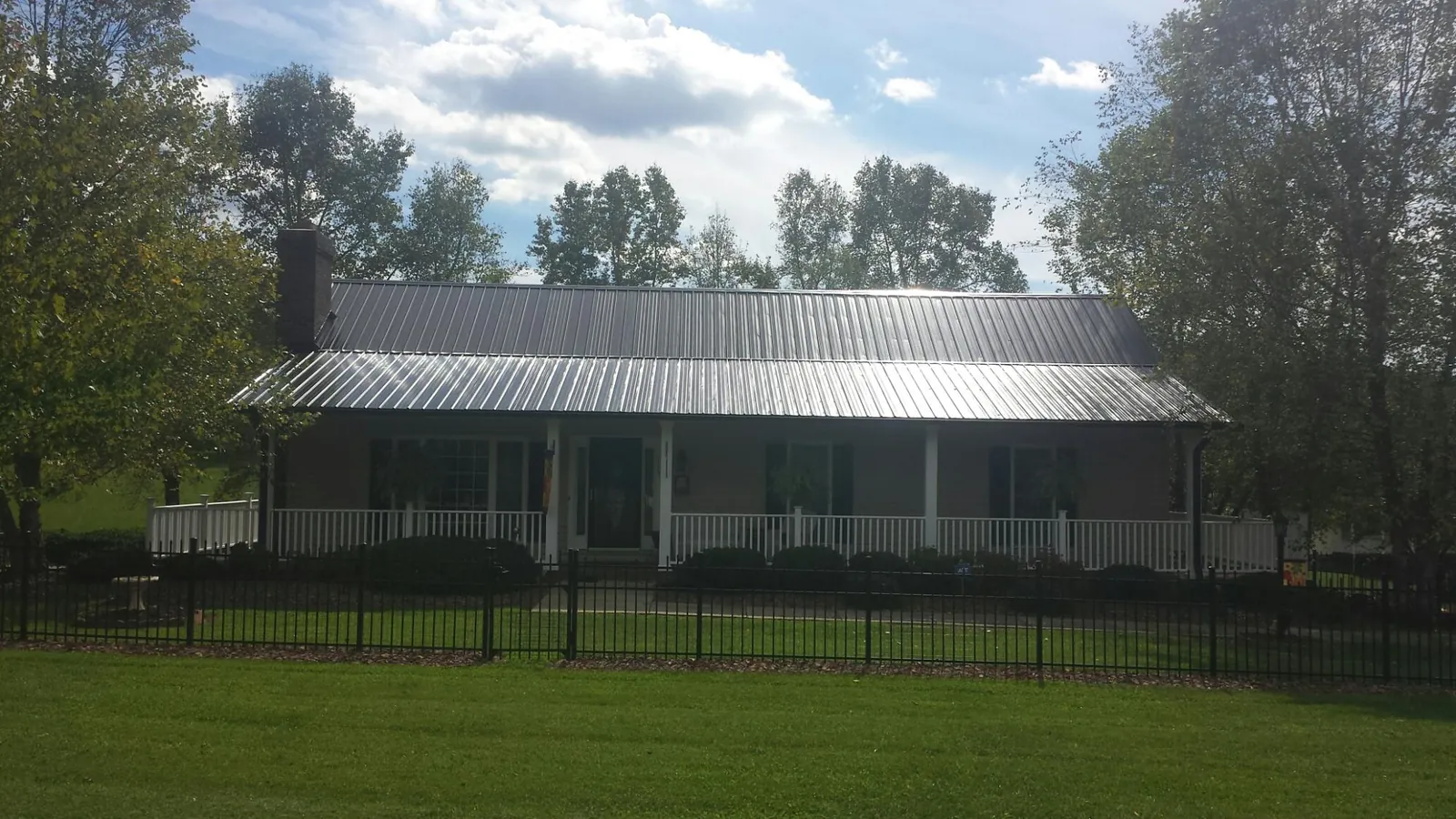 Gray metal roof on a brick ranch with a full width front porch — Gutter Guard Installation work by our crew in Ozawkie