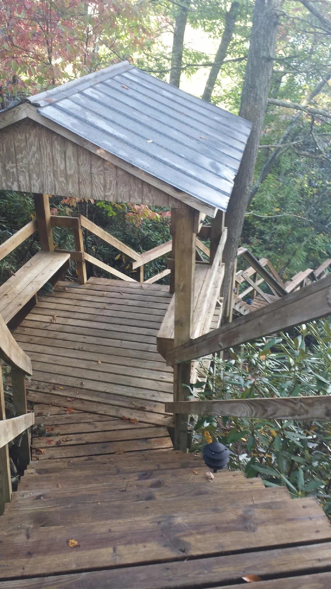 Metal roofed shelter over wooden steps on a wooded walkway — Skylight Repair & Installation work by our crew in Ozawkie